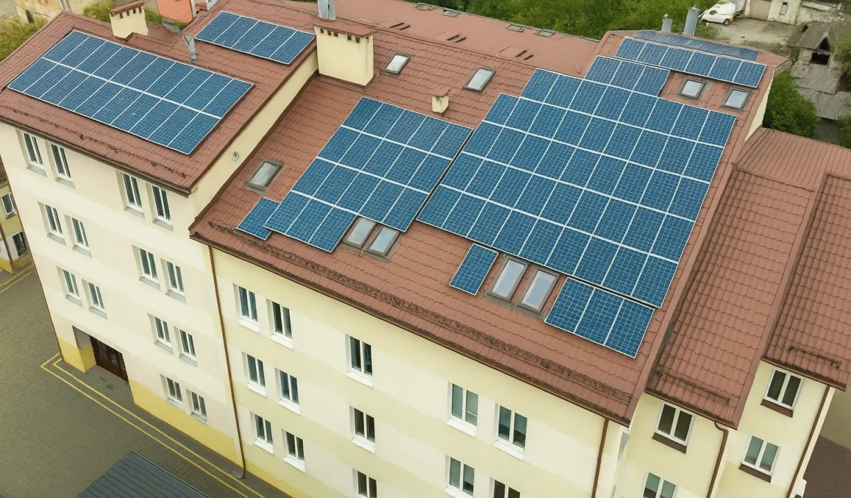 bytový dům s instalovanými fotovoltaickými panely na střeše, pohled z dronu